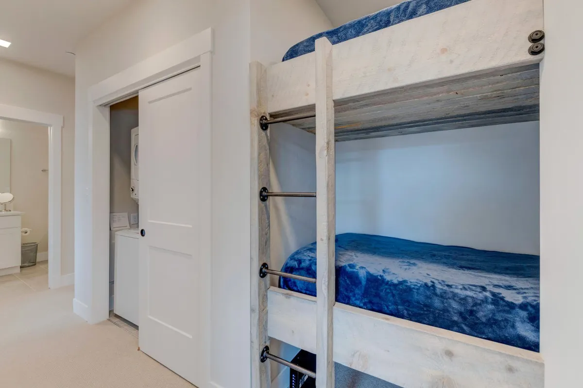 A playful bunk bed area with a view into a laundry space, designed for family-friendly stays. The informal, shared bedroom setup is ideal for kids or groups, highlighting flexible sleeping arrangements.