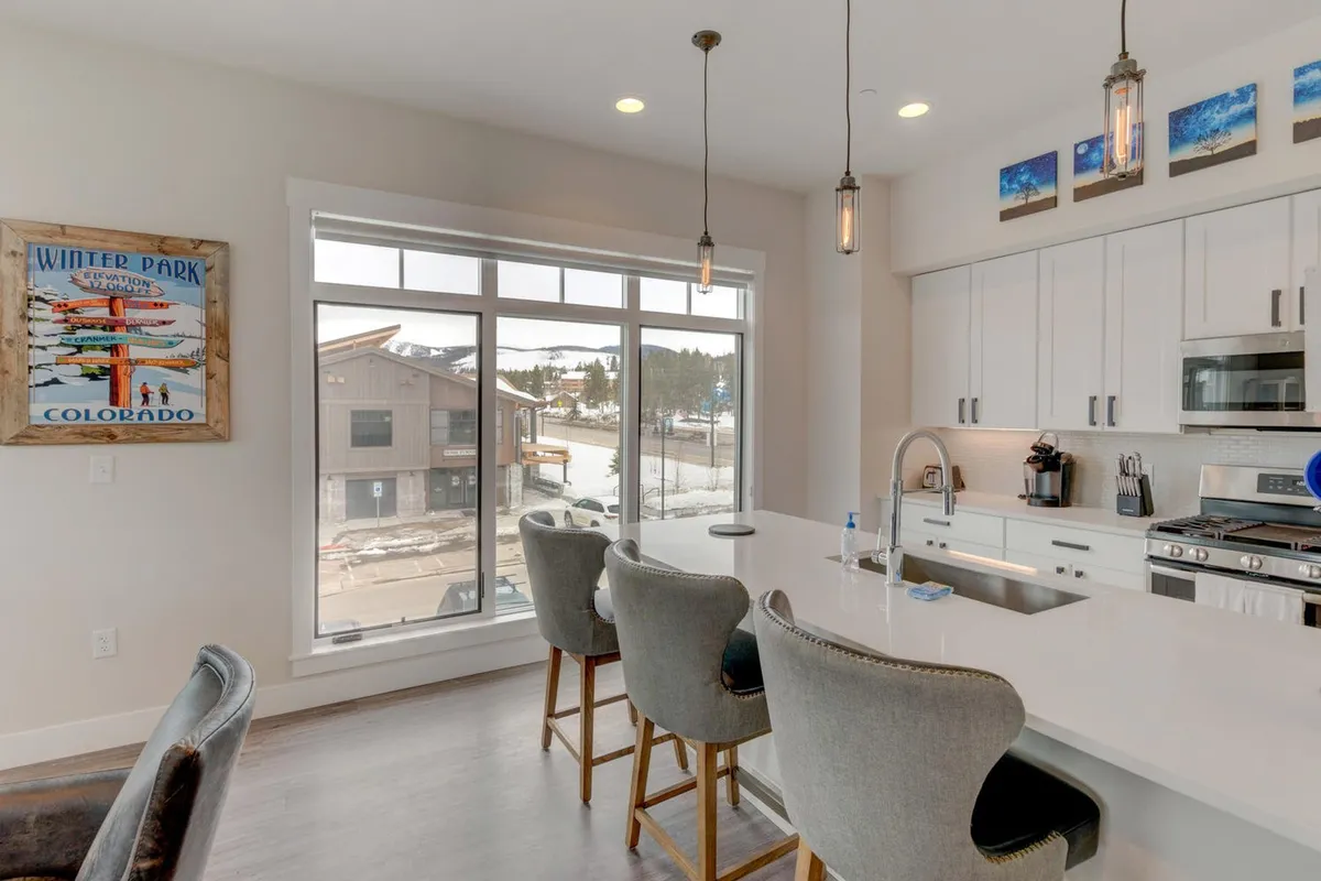 A welcoming kitchen and dining area with large windows, a kitchen island, and bar stools. Natural light pours in, suggesting a sociable space perfect for sharing meals or morning coffee while taking in sunrise views.