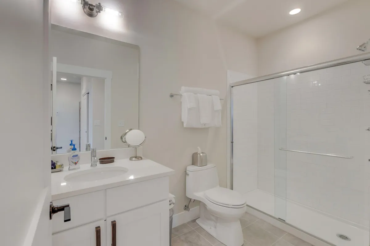 A modern bathroom featuring a stylish vanity with sink, glass-enclosed shower, toilet, and a well-lit mirror. The fresh, inviting atmosphere is enhanced by plush towels and high-end toiletries.